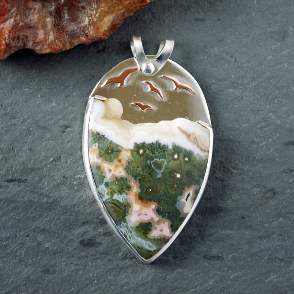 Ocean jasper pendant with copper birds flying above stone