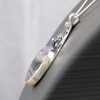 Silver pendant with Amethyst in Quartz cabochon, silver falling star above stone, close-up