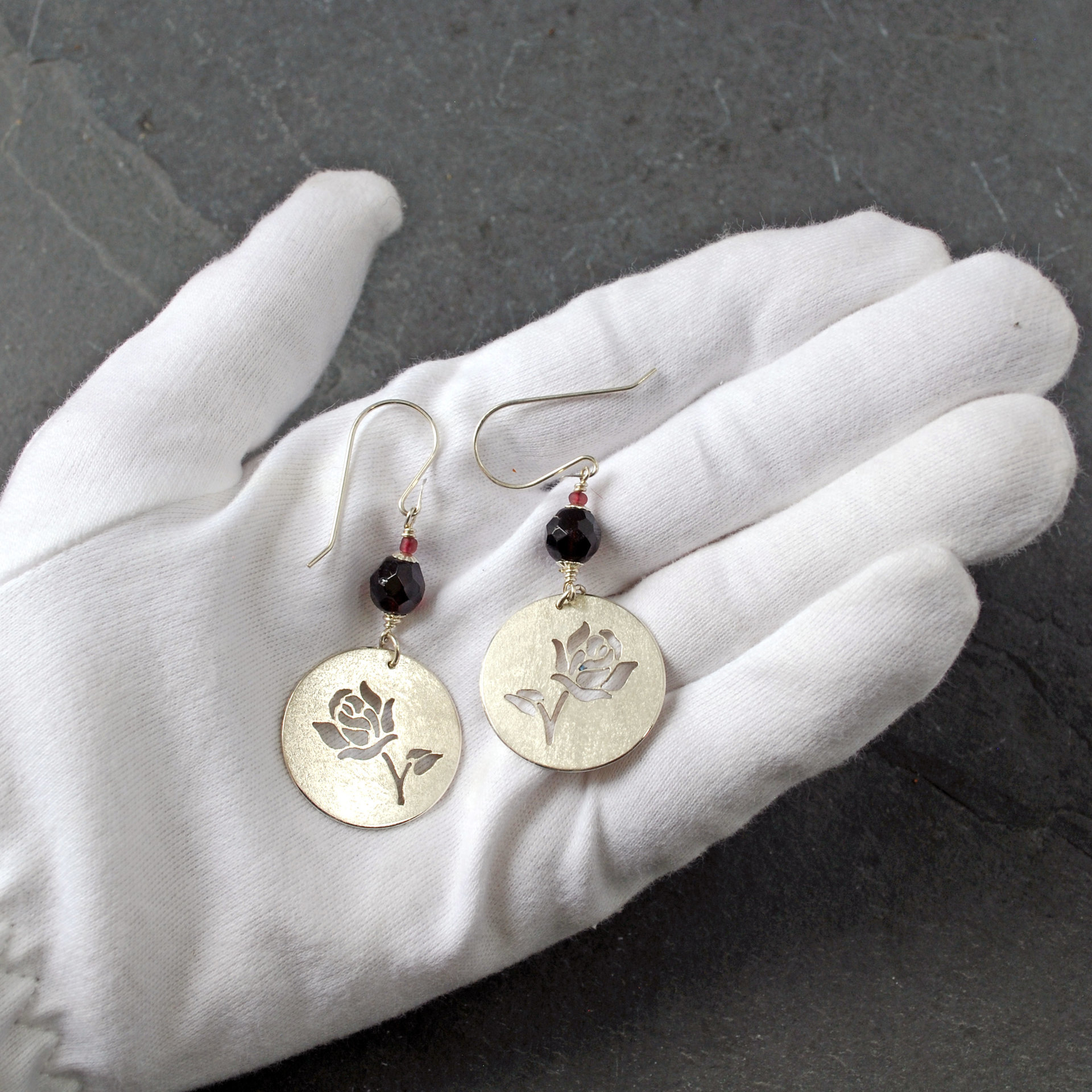 Silver Rose cut-out garnet earrings, in hand