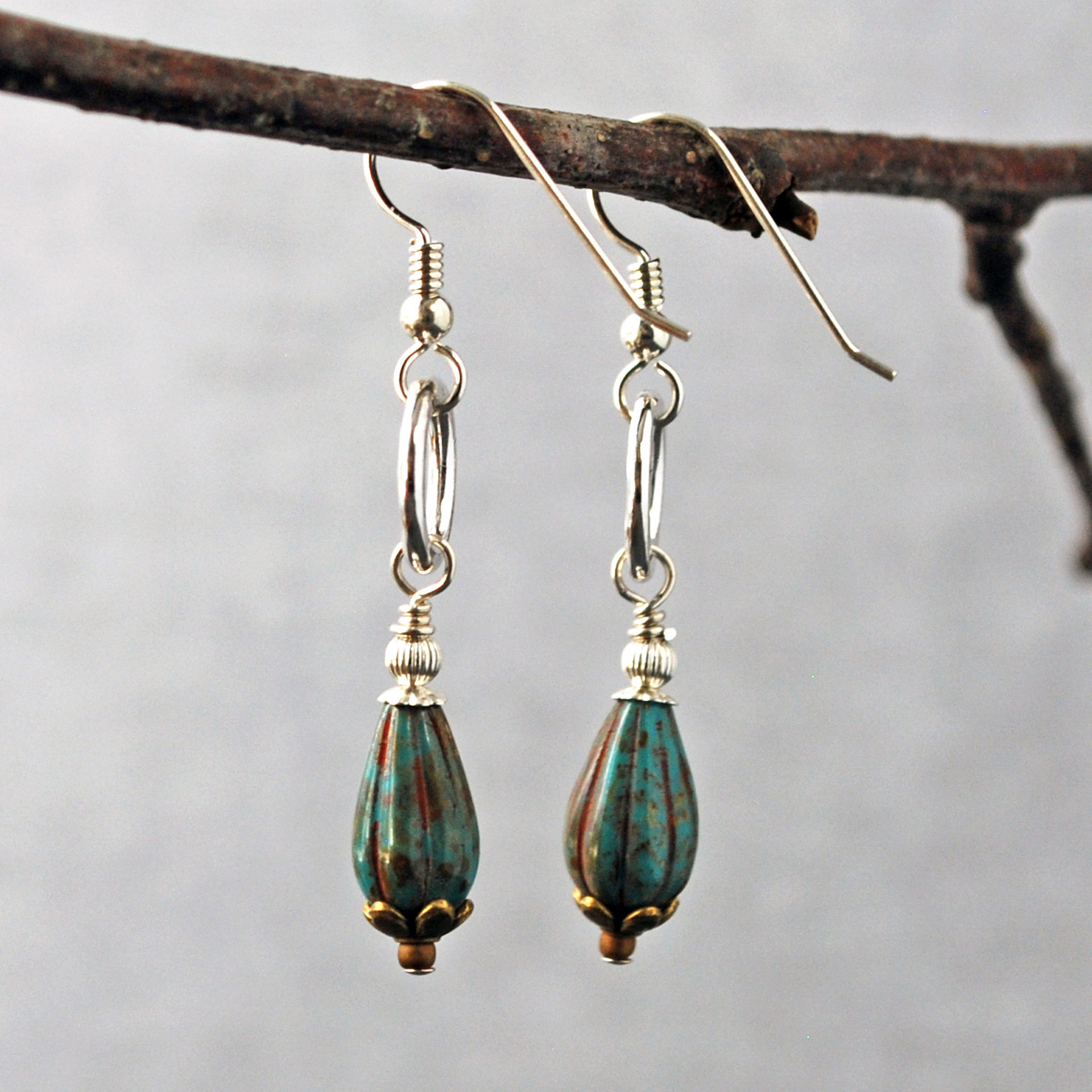 Silver ring and Czech glass teal earrings hanging-side view