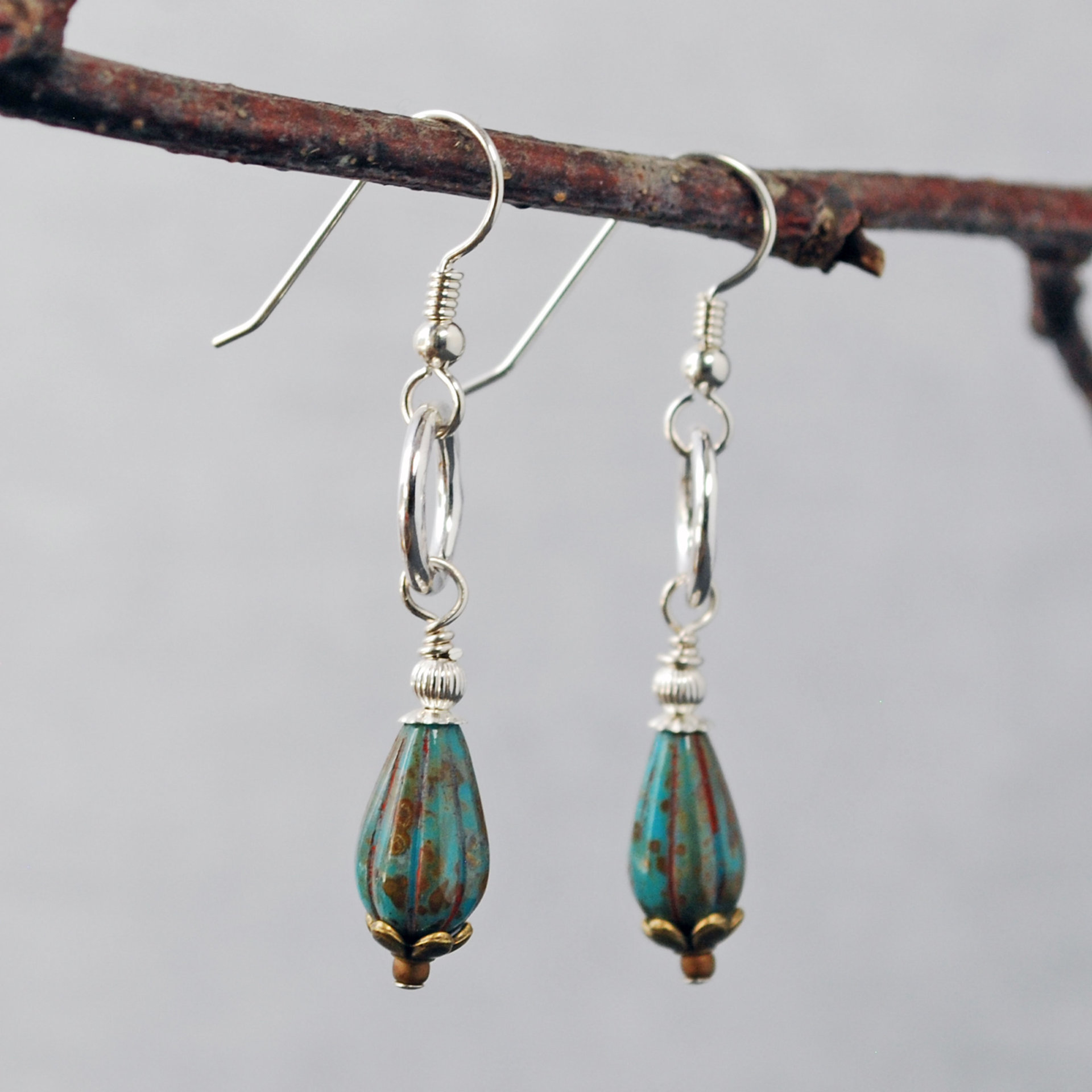 Silver ring and Czech glass teal earrings hanging-side view