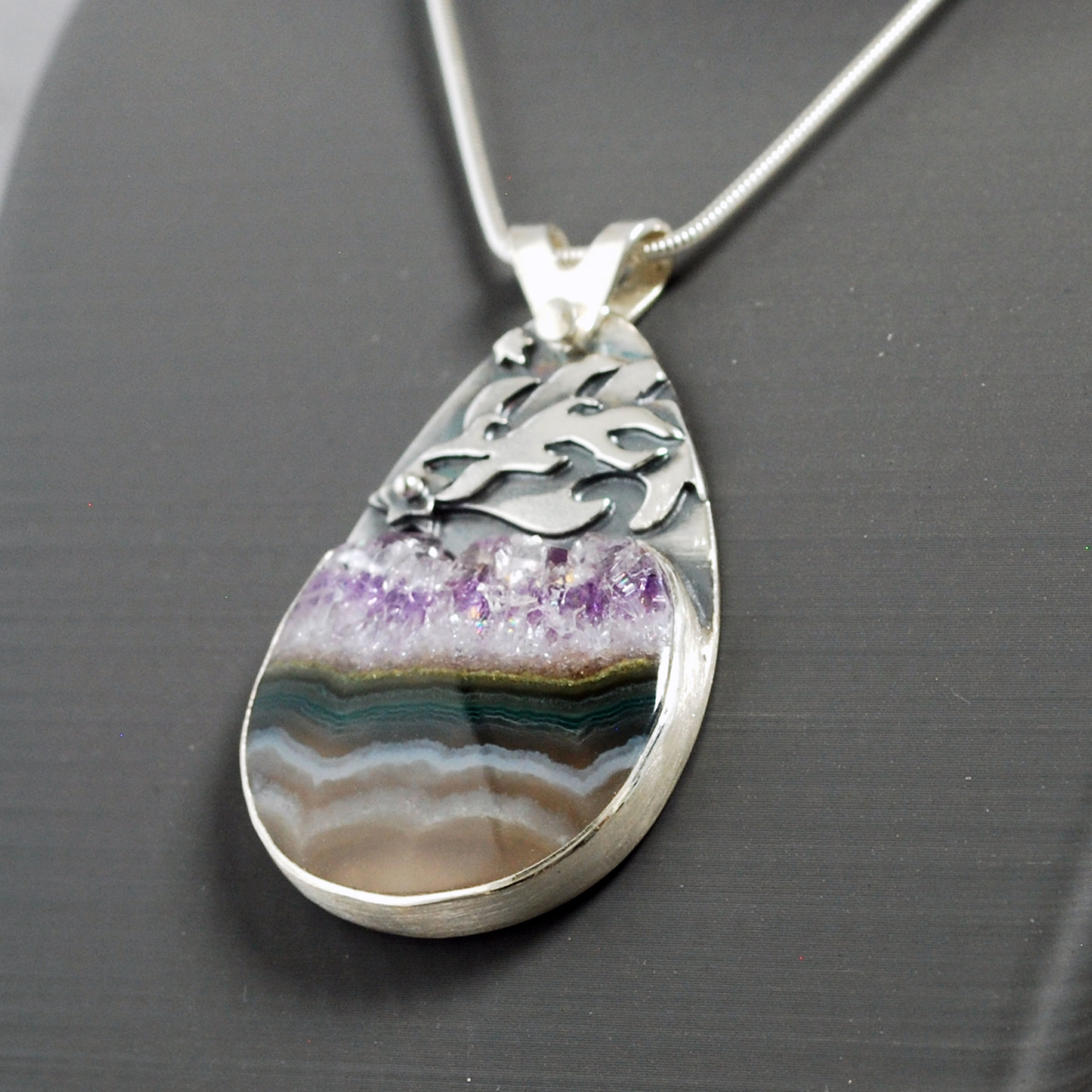 Silver pendant with Amethyst in Quartz cabochon, silver falling star above stone, close-up