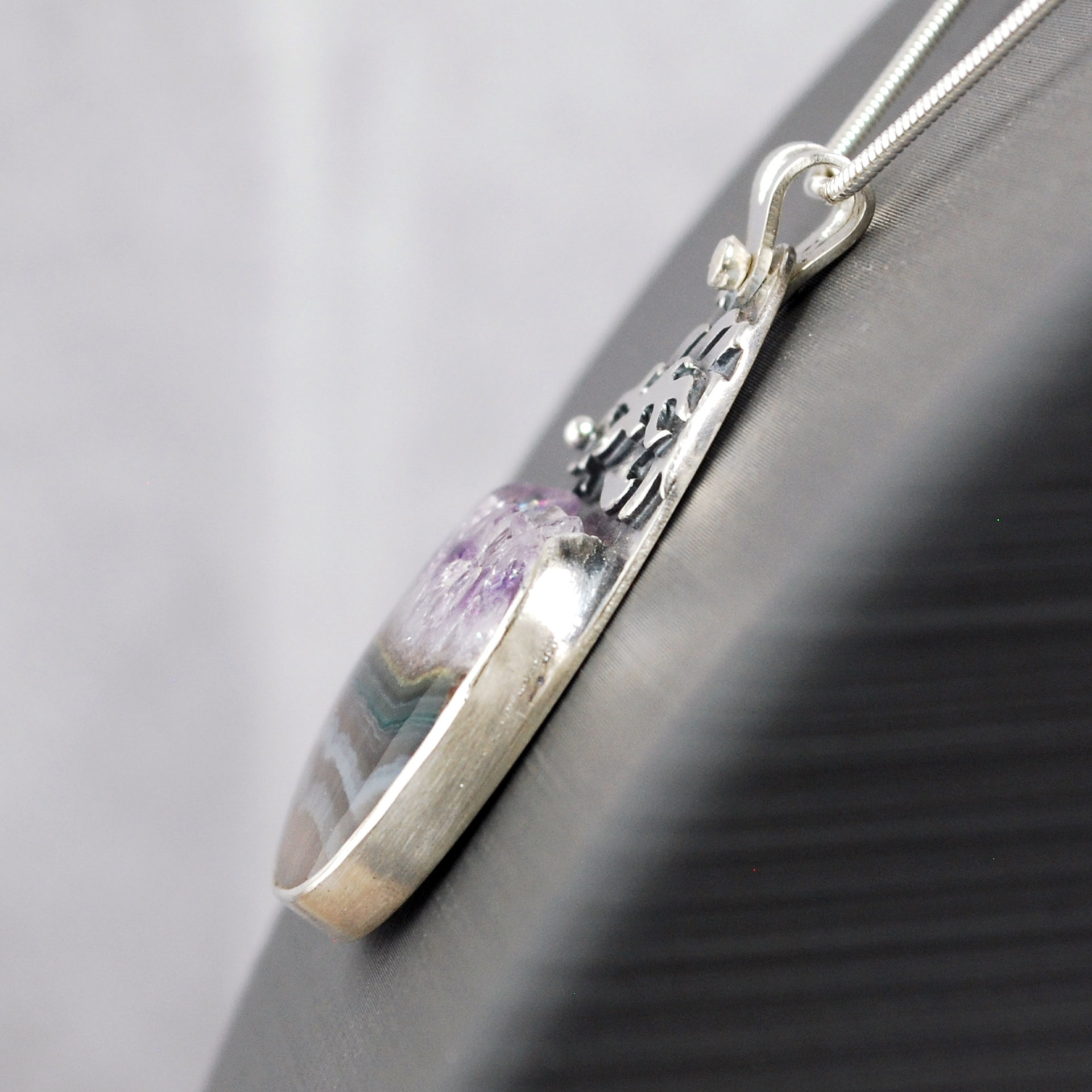Silver pendant with Amethyst in Quartz cabochon, silver falling star above stone, close-up