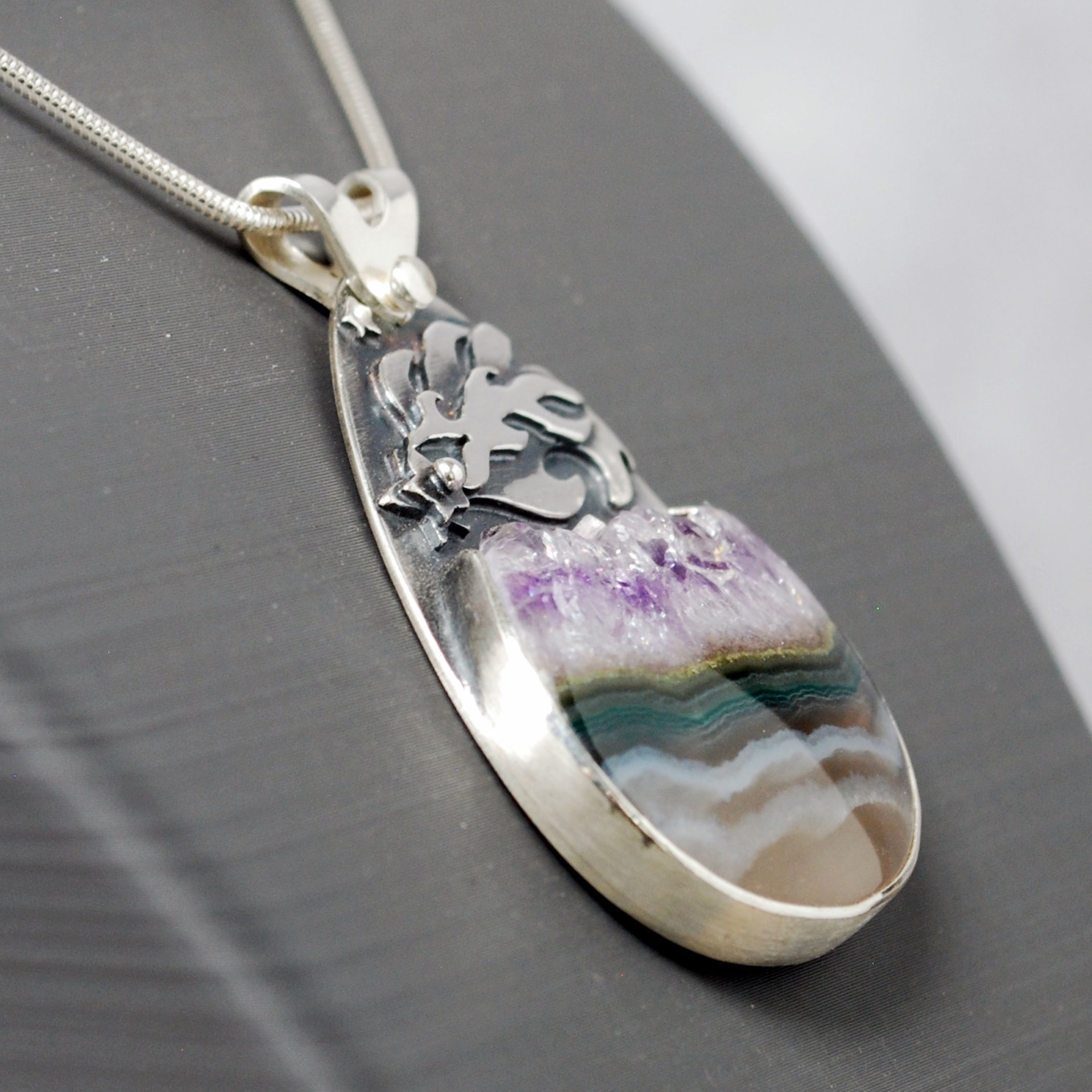 Silver pendant with Amethyst in Quartz cabochon, silver falling star above stone, close-up