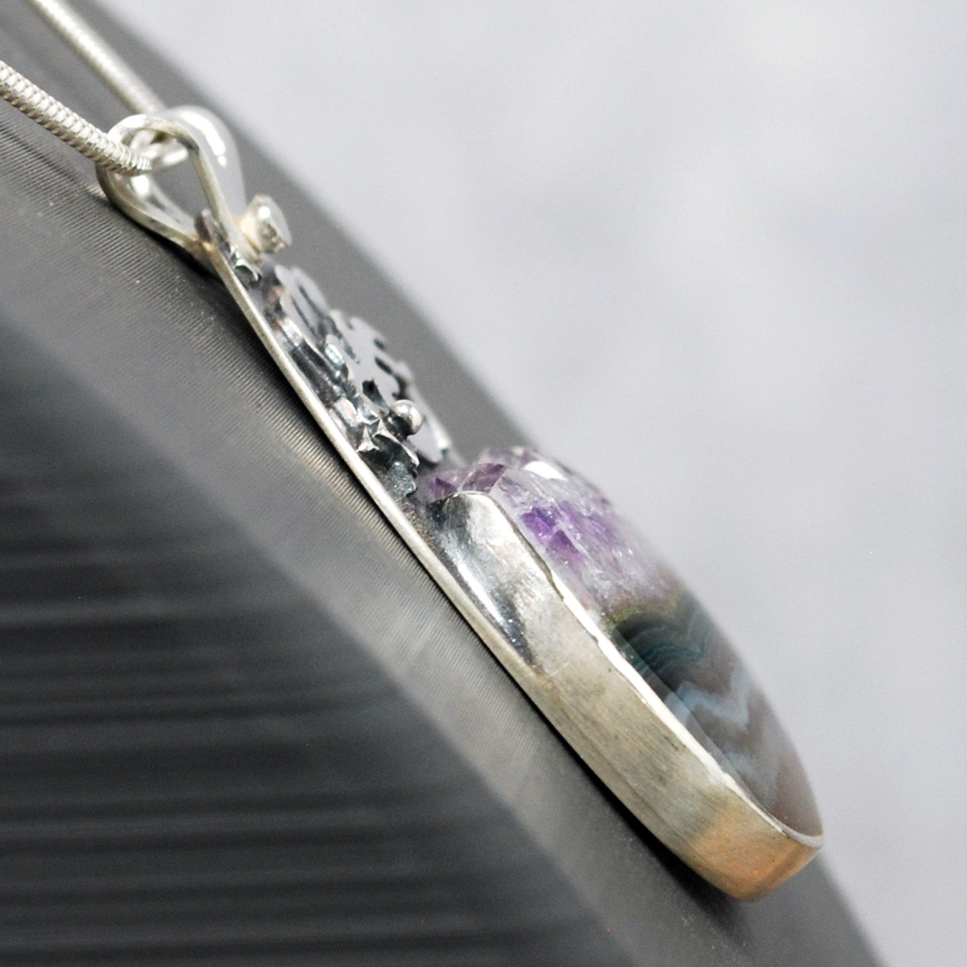 Silver pendant with Amethyst in Quartz cabochon, silver falling star above stone, close-up