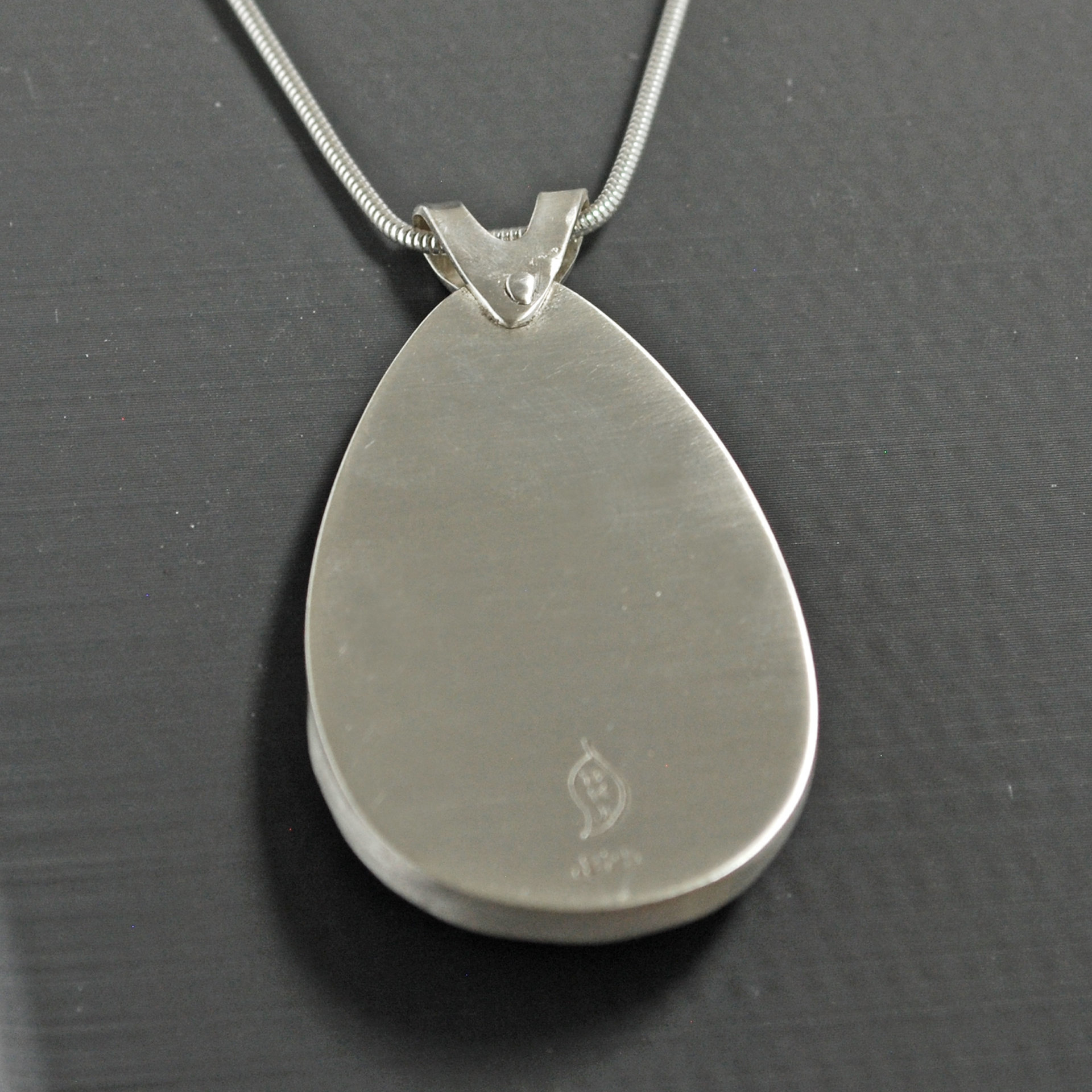 Silver pendant with Amethyst in Quartz cabochon, silver falling star above stone, close-up